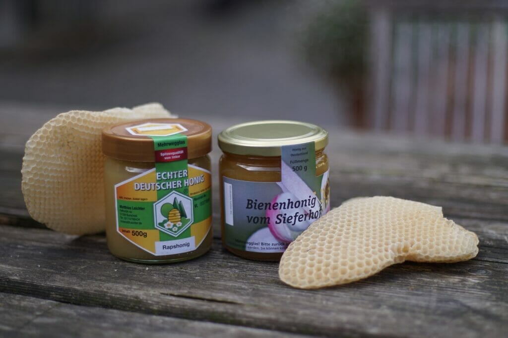 2 Gläser Honig mit Waben auf einem Tisch
